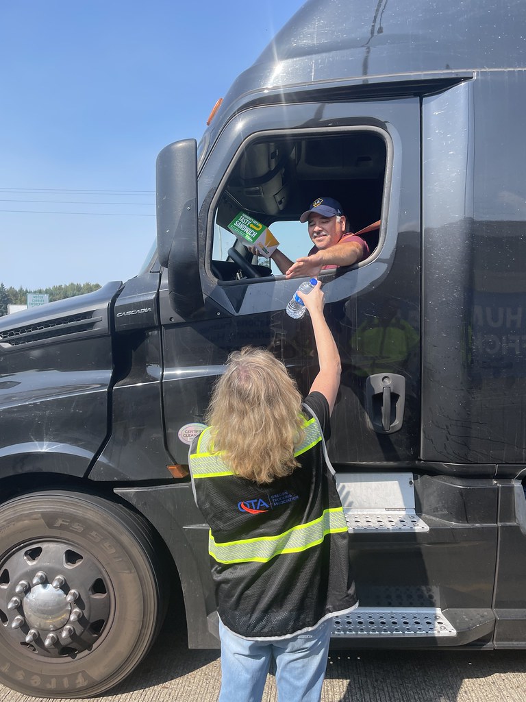 Smiling driver in a black Freightliner semi-truck