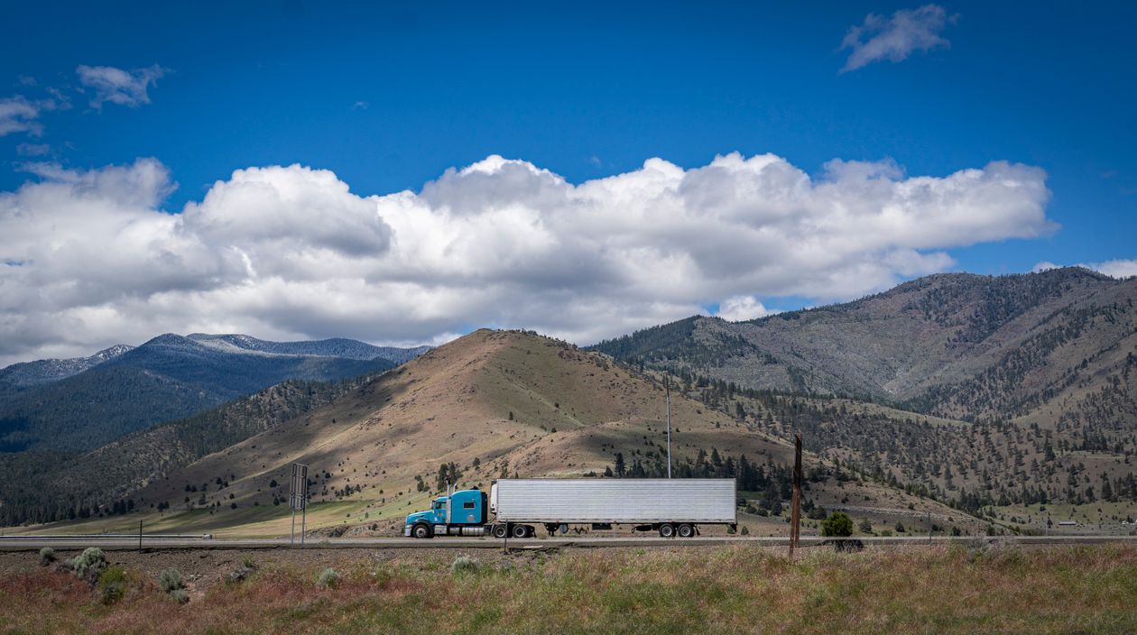 American semi-truck travelling through mountain scenery